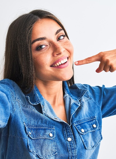 Smiling woman pointing to her white teeth