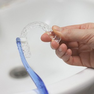 Patient using toothbrush to clean aligner