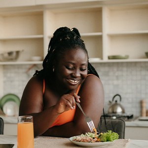 Woman smiling while eating healthy in kitchen