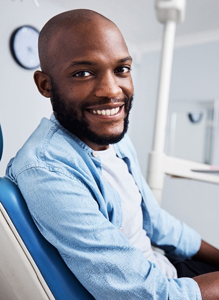 Male dental patient sitting in chair and smiling