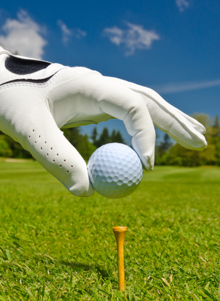 gloved hand placing a golf ball on a tee