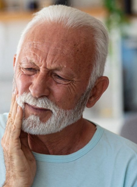 Senior bearded man rubbing jaw in pain