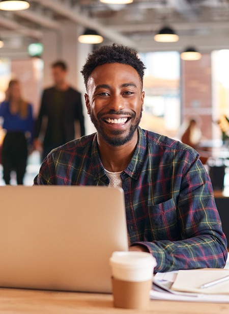 a person smiling and working on their laptop in an office