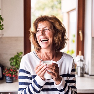 person holding a cup of coffee in their hands while standing in their kitchen