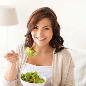 Woman eating green salad sitting down