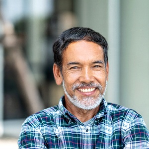Man in plaid smiling outside with gray beard