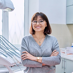 Woman with glasses standing in a dental office and smiling