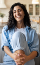 Woman smiling while holding up her Invisalign aligner