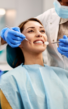 Woman looking at her smile in a handheld mirror after dental treatment