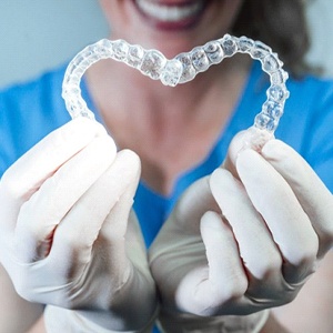 dentist holding two Invisalign aligners in the shape of a heart