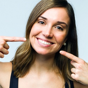Woman looking at camera and pointing to her smile