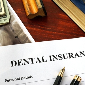 Dental insurance paperwork on desk with pen and X-ray
