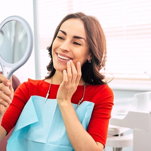 Woman with Invisalign in Manchester smiling into a mirror