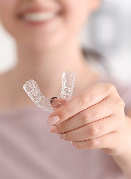 Woman holding up an Invisalign tray