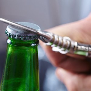 person opening a green glass bottle with a bottle opener 