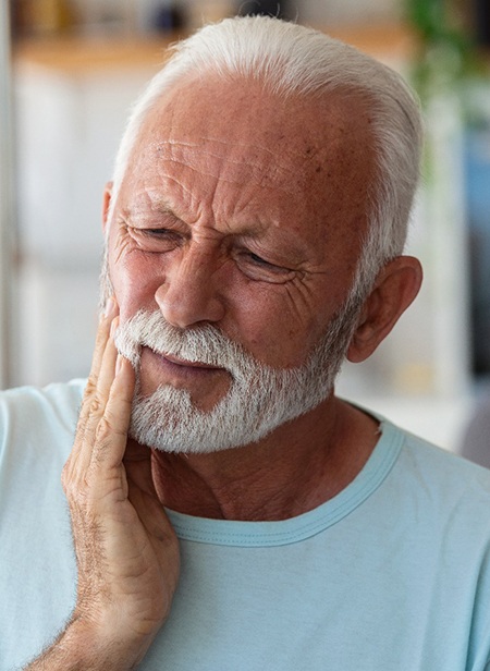 Male in light blue shirt rubbing jaw in pain