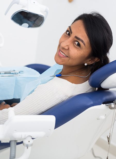 Young woman sitting in dental chair and smiling