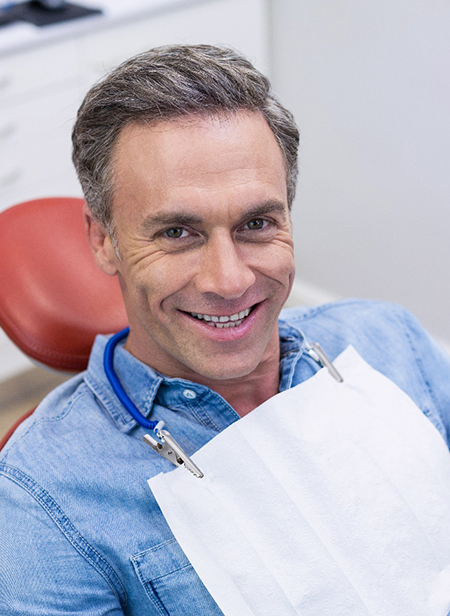 Older man in denim jacket sitting in dental chair