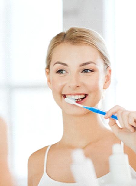 Woman smiling while brushing her teeth