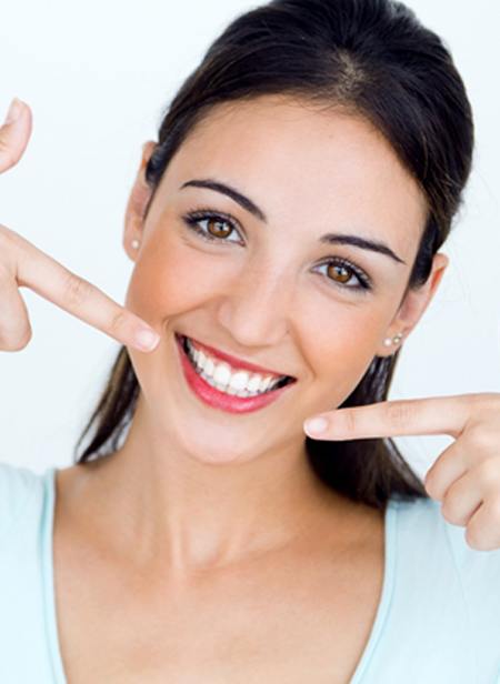 A woman pointing at her smile. 