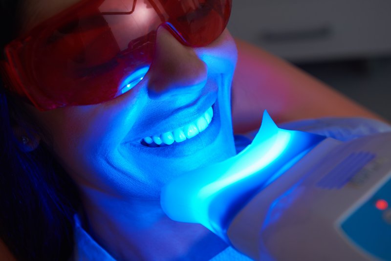 Smiling woman getting professional teeth whitening in Manchester