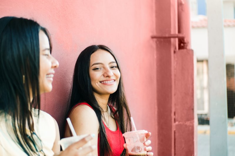 young woman smiling while drinking smoothie