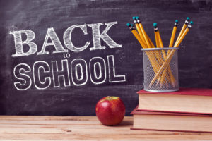 a chalk board with the words "back to school" written on it and a container full of pencils next to an apple on a desk