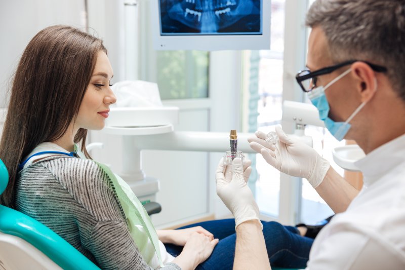 A dentist talking with his patient about why her dental implants are loose