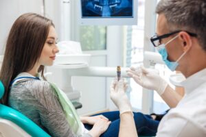 Dentist showing patient a dental implant. 