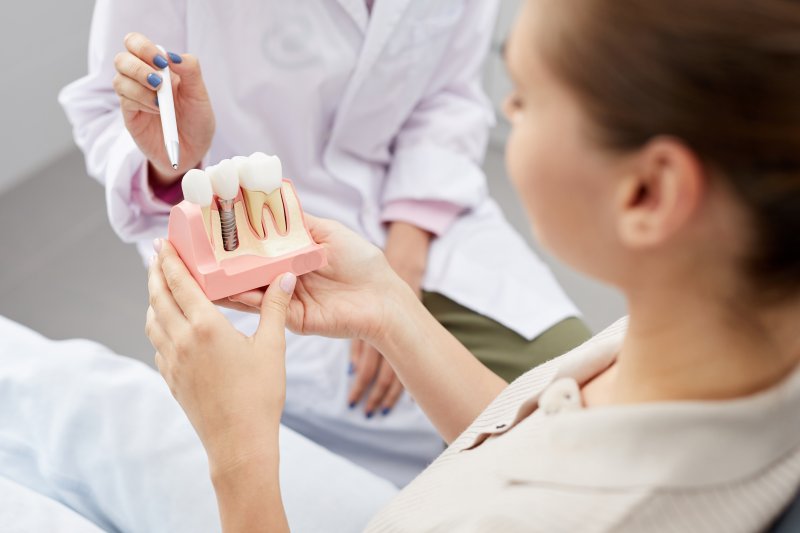 A dentist showing a dental implant model to his patient