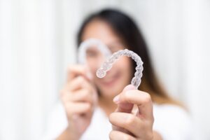 Woman holding up her clear aligners